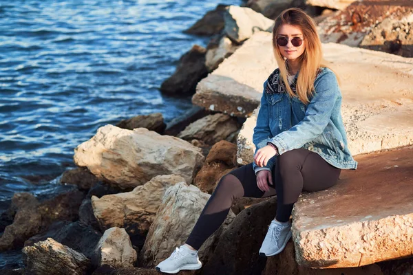 Menina Bonita Óculos Sol Senta Uma Pedra Junto Mar Vestindo — Fotografia de Stock