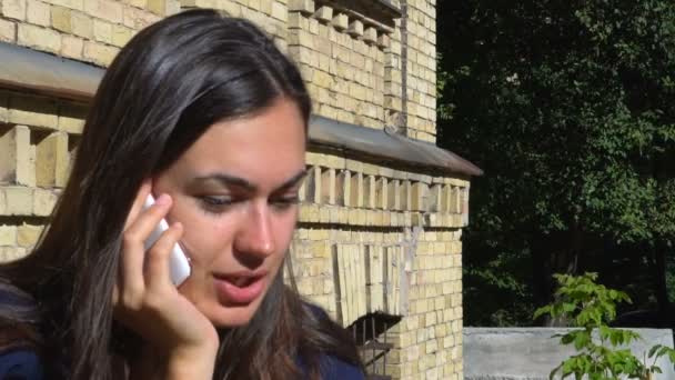 Mladá dívka mluví po telefonu mimo staré budovy — Stock video