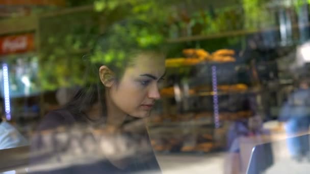 Девушка с ноутбуком в кафе пьет кофе — стоковое видео