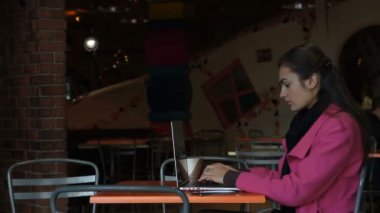 Telefonda konuşurken kafede masada dizüstü bilgisayar ile genç kız