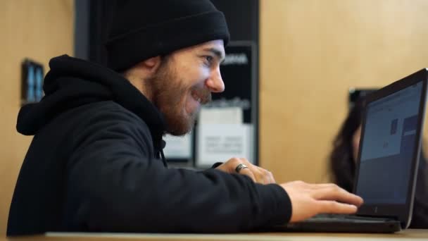 Un joven que trabaja con un portátil en un café — Vídeos de Stock