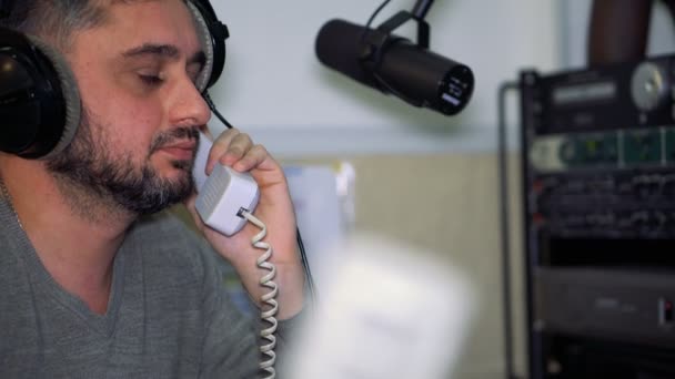 Radio presenter at the microphone in a live radio broadcast studio — Stock Video