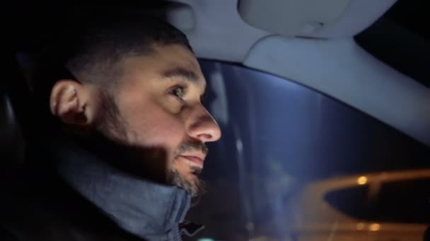 Hombre al volante de un coche conduciendo por las calles nocturnas — Vídeo de stock