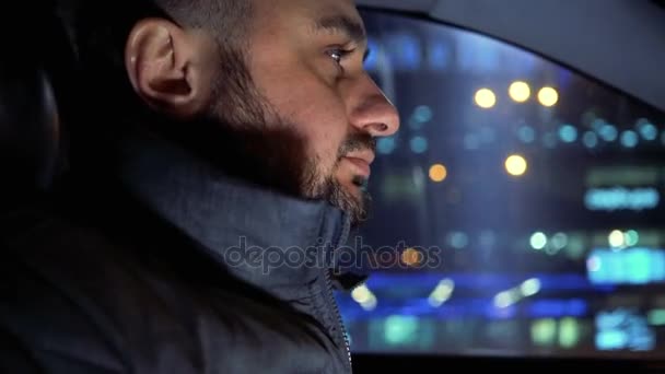 Hombre al volante de un coche conduciendo por las calles nocturnas — Vídeo de stock