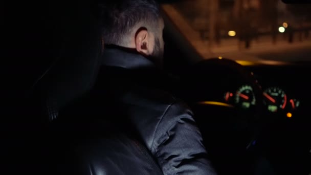 Hombre al volante de un coche conduciendo por las calles nocturnas — Vídeos de Stock