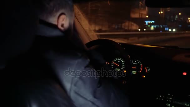 Hombre al volante de un coche conduciendo por las calles nocturnas — Vídeo de stock