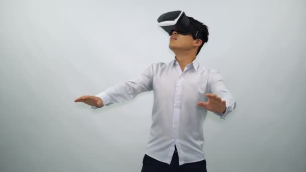 Homem jovem vestindo fone de ouvido VR em um fundo branco — Vídeo de Stock
