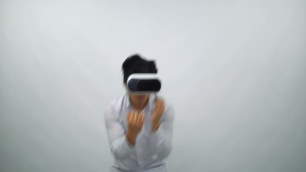 Jovem luta em óculos de realidade virtual em um fundo branco — Vídeo de Stock