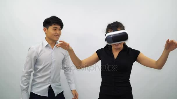 Menina e cara asiático vestindo fone de ouvido VR em um fundo branco — Vídeo de Stock