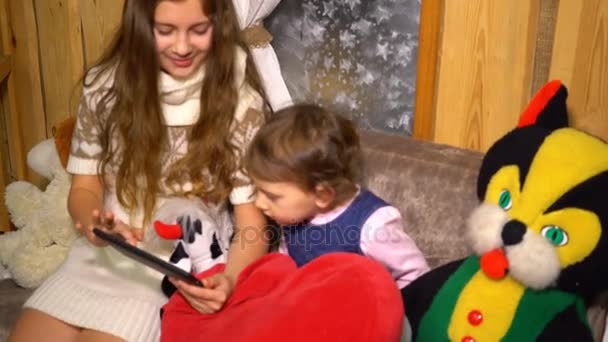 Девочка использует планшет с младшей сестрой дома — стоковое видео