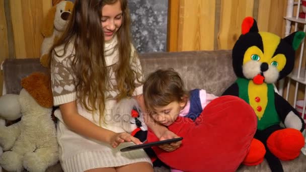 Teen girl uses tablet with little sister at home — Stock Video