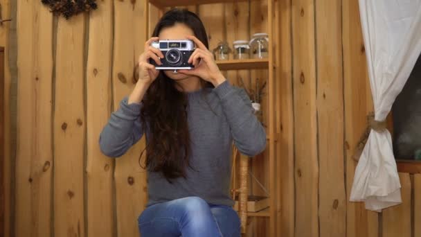 Joven chica morena haciendo foto en la cámara retro en casa — Vídeos de Stock