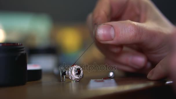 Masters hand applies the red enamel on the silver ring with a special tool — Stock Video