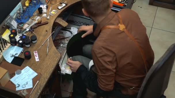 Κοσμηματοπωλείο σηκώνεται από το τραπέζι με τα εργαλεία και πηγαίνει στο μηχάνημα λείανσης — Αρχείο Βίντεο