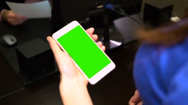 Девушка держит зеленый экран телефона, пока босс читает контракт — стоковое видео