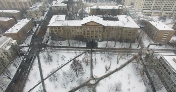 Edificio universitario con nieve voladora y personas en movimiento — Vídeo de stock