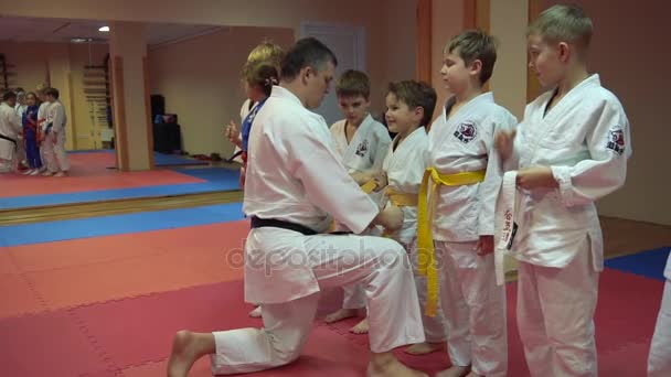 Kyjev, Ukrajina - 6 února 2017: Mentor před začátkem tréninku karate juniorů utáhnout opasek kid — Stock video