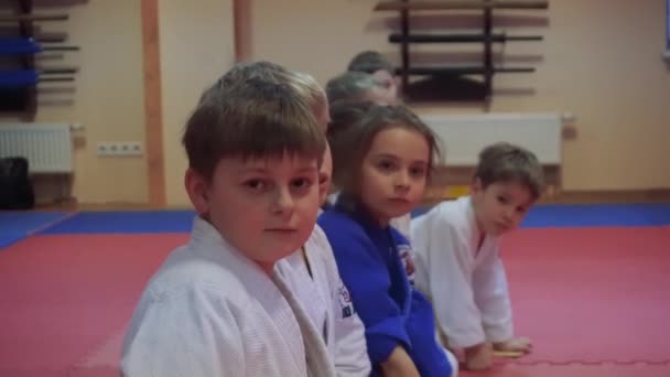 Kiev, Oekraïne - 6 februari 2017: Kids sporters in kimono op tatami zitten en kijken in de camera — Stockvideo