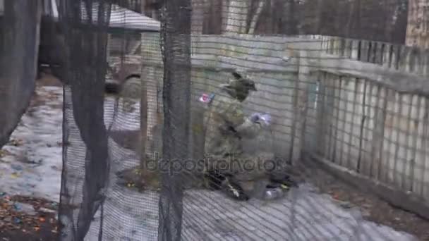 KIEV, UCRAINA - 4 marzo 2017: Il giocatore di paintball in maschera lancia una granata oltre un recinto — Video Stock