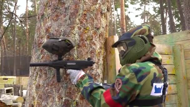 Kiev, Ukrajna - 2017. március 4.: Paintball játékos lő az ellenség, és a fa mögött bújik meg a támadás után — Stock videók