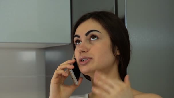 Chica morena con frenillos hablando por teléfono y mirando hacia arriba — Vídeo de stock