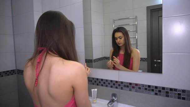 Girl puts cream on face for makeup preparation standing in bathroom — Stock Video
