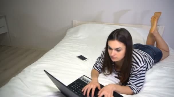 Freelancer girl is working at home lying on the bed — Stock Video