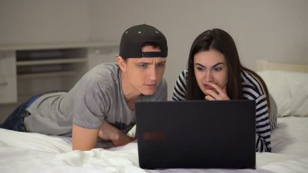 Девушка в брекетах приглашает парня к ноутбуку, чтобы обсудить отличные новости — стоковое видео