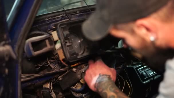Muž v čepici a s tetováním opraví auto — Stock video