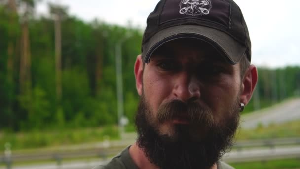 Man met een baard en in een cap op een groene achtergrond — Stockvideo