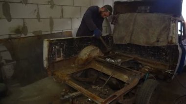 Araba tamircisi çalışan bir çekiç kullanarak bir paslı araba vücut yener