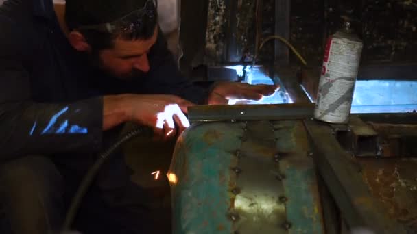 Homem na garagem trabalha com uma máquina de solda — Vídeo de Stock