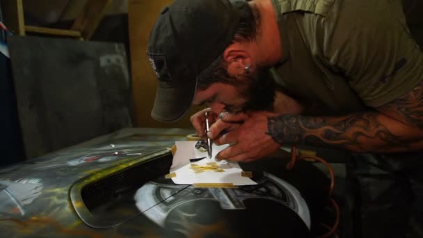 Painter of the workshop creates aerography on the hood car — Stock Video