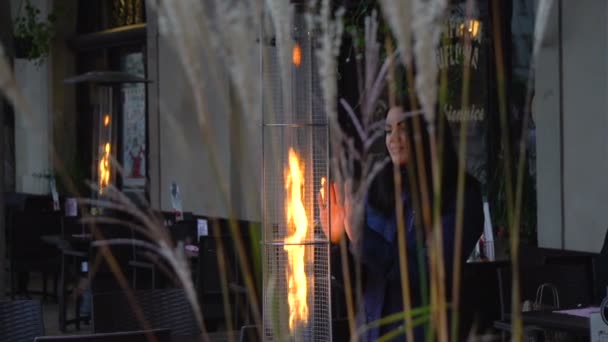 크 라 코 프, 폴란드-10 월 8 일, 2017: 소녀 거리 적외선 가스 히터의 불꽃 근처 그녀의 손을 따뜻하게합니다 — 비디오