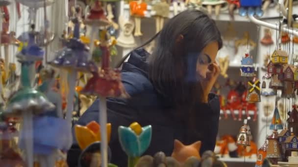 ギフトの店先でブルネットの少女がお土産を選択するクラクフ、ポーランド - 2017 年 10 月 8 日。 — ストック動画