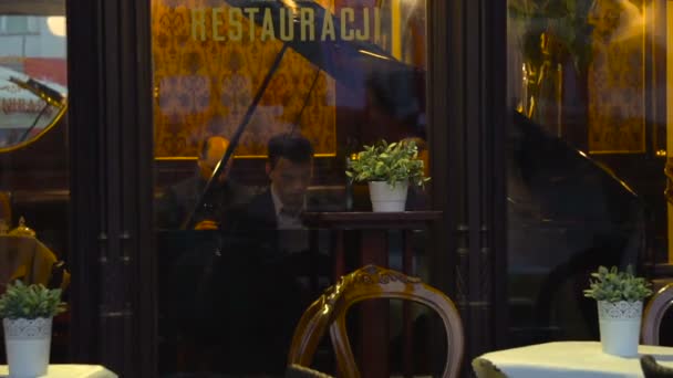 Cracovie, Pologne - 8 octobre 2017 : Pianiste joue et couple amoureux s'embrassent dans la devanture du restaurant — Video