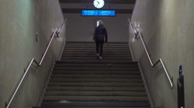 Kız merdivenlerden tren istasyonu platformu için tırmanıyor.