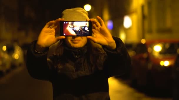 Menina está fazendo uma foto selfie em uma cidade noturna na rua — Vídeo de Stock