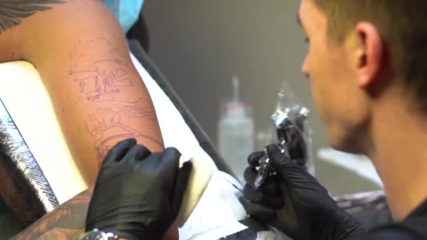 Τατουάζ πλοίαρχος αρχίζει να εργάζεται για το τατουάζ σύμφωνα με σκίτσο — Αρχείο Βίντεο