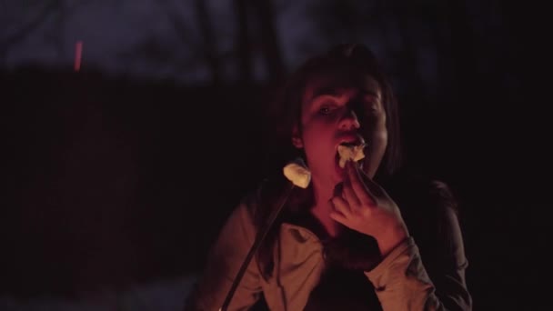 Guimauve à la flamme soirée repos fille mange guimauve et sourit joyeusement 