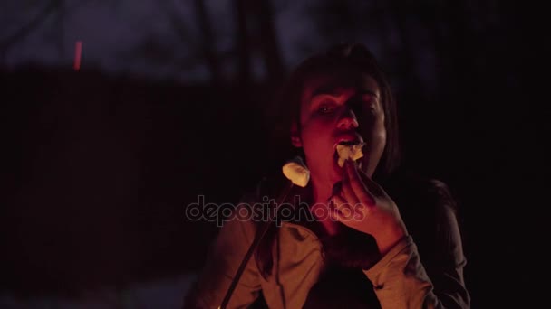 女孩在火中享受棉花糖和开朗吃它 — 图库视频影像