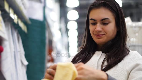 Menina morena em uma loja têxtil escolhe toalha — Vídeo de Stock