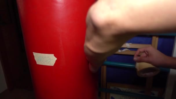 L'homme fait une marque sur le sac de boxe pour son petit fils — Video