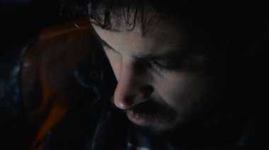 Adam bir smartphone ve onun yüzüne yansıyan ışık görünüyor