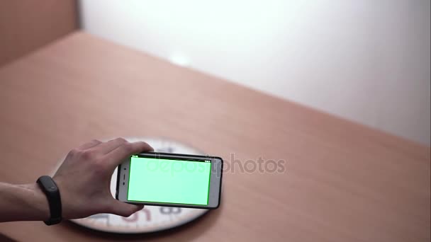 Smartphone escanea el reloj de pared moviendo la mano a la derecha a la izquierda a lo largo del reloj con pantalla verde — Vídeo de stock