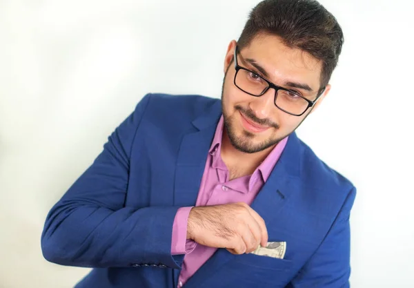 Sakallı genç gülümseyen işadamı portresi takım elbise beyaz arka plan üzerinde cebinde para dışarı alır