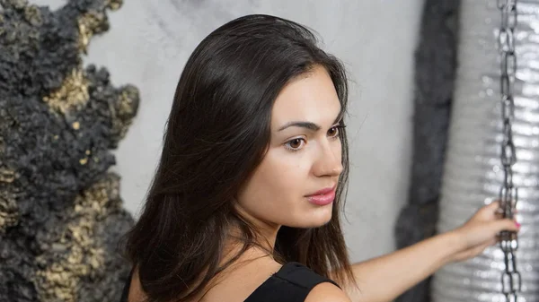 Seyir sırt bir kenara zincirlerle salıncakta oturan genç esmer kız portresi