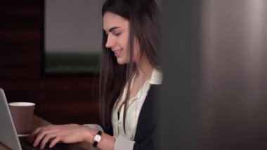 Esmer kız dizüstü bilgisayarda yazarak ve kahve içme Skype konuşuyor