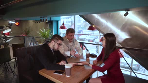 Adult man hugging a guy and a girl sitting in a cafe after a friendly conversation — Stock Video