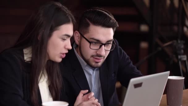 Dos compañeros de trabajo discutiendo casos en una pausa para el café con un portátil — Vídeos de Stock